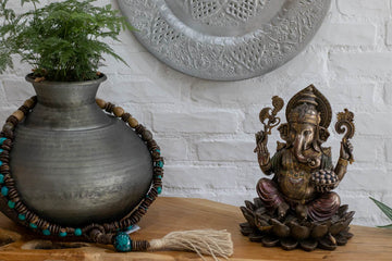 Decoração de hall de entreda com aparador de madeira vaso de planta e mandala de metal com japamala combinando com a escultura bronze do deus hindu Ganesh 