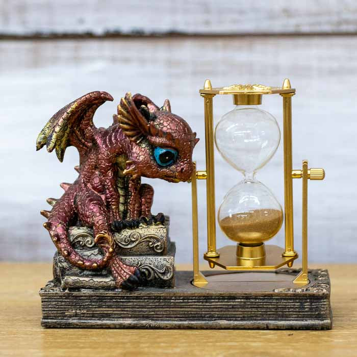 Ampulheta decorativa em bronze com escultura de bebê dragão vermelho detalhado abraçando a base de vidro.