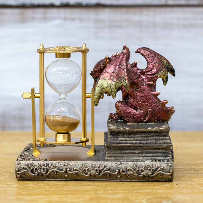 Peça decorativa esotérica de dragão em bronze em um ambiente de biblioteca com livros e iluminação suave.